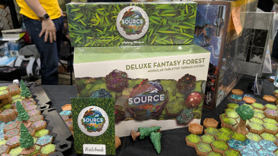 Deluxe Fantasy Forest convention booth — Fantasy Forest box, rulebook and partial green hex map with pink flowering moss tiles, edge pieces and pine trees